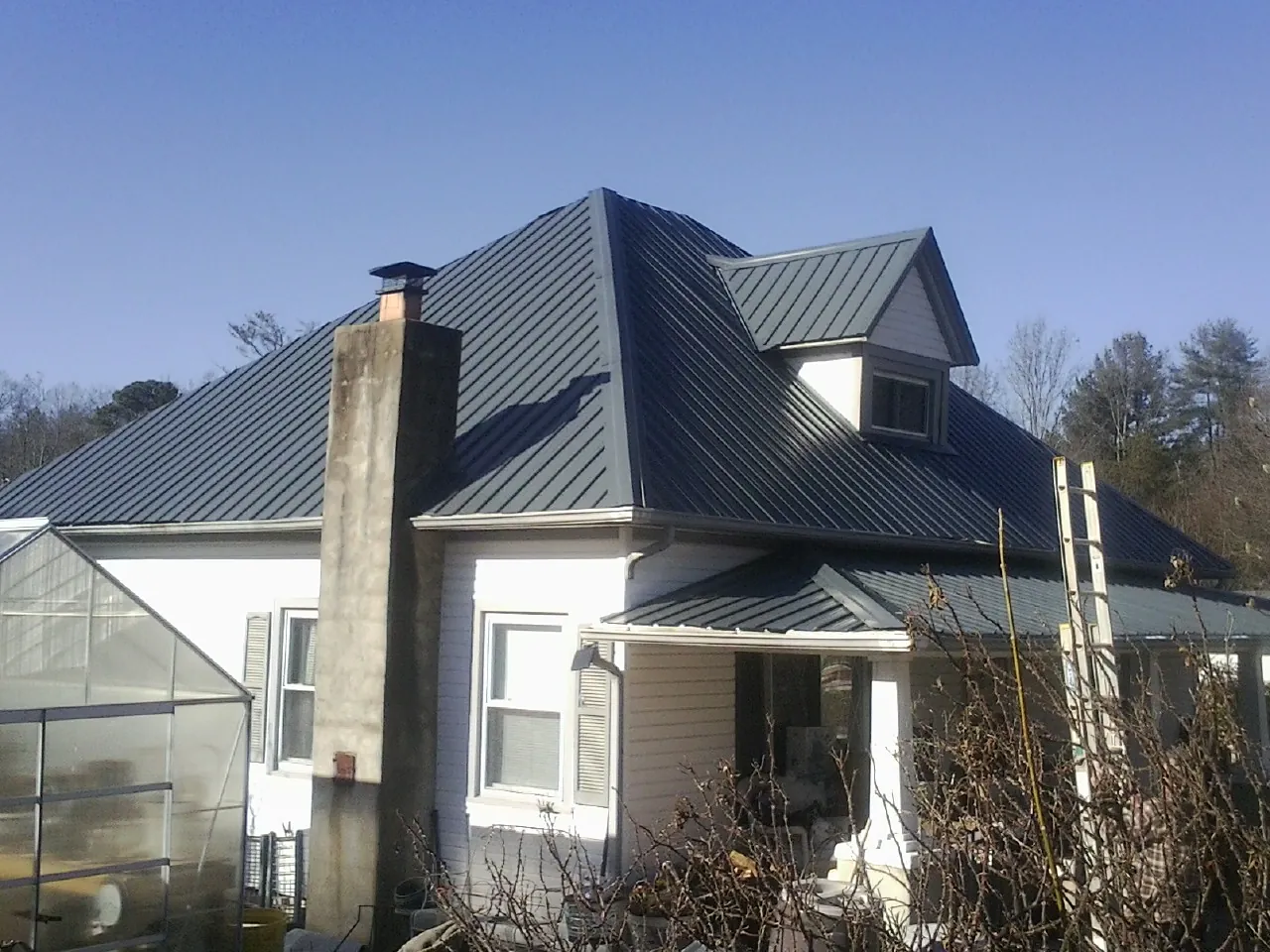 Dark blue standing seam metal roof on a white farmhouse with dormer — Slate & Tile Roof Repair by Roofing Brothers in Newton Hamilton