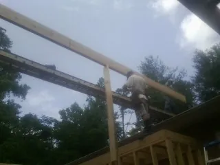 Carpenter setting a ridge beam over a new addition frame — Ice Dam Removal by Roofing Brothers in Newton Hamilton