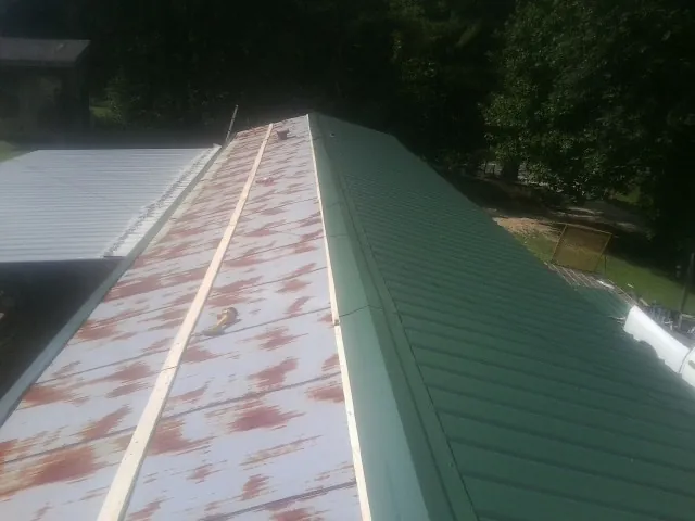 Old rusted panels beside newly installed green metal roofing — Wind Damage Roof Repair by Roofing Brothers in Newton Hamilton
