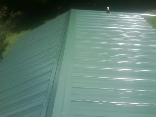 New green metal panels meeting at the ridge of a roof — Flat Roof Repair work by our crew in Newton Hamilton