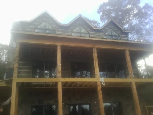 Dormers and porch framing on a large log home under construction — Roof Coating work by our crew in Newton Hamilton