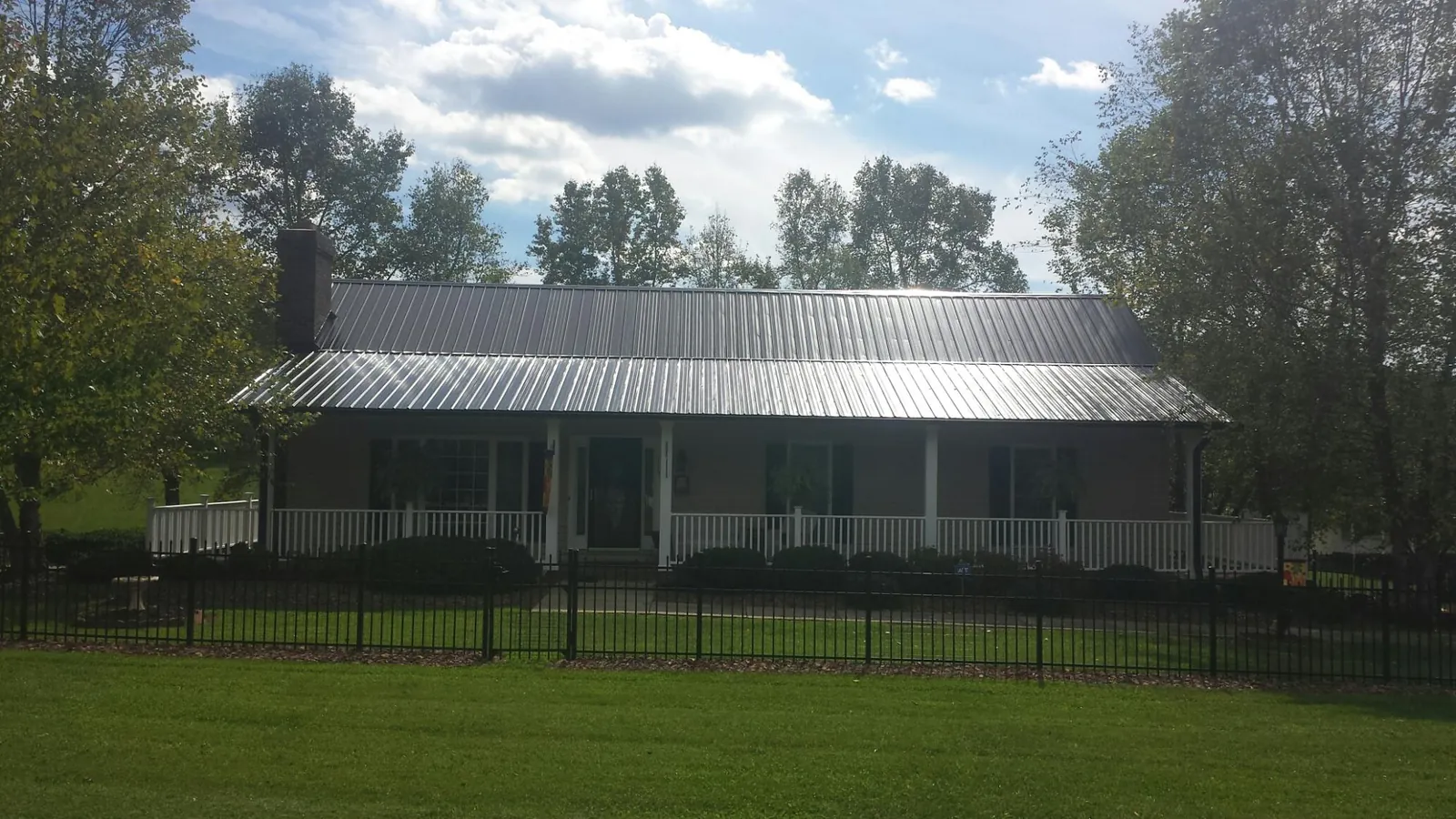 Gray metal roof on a brick ranch with a full width front porch — Gutter Guard Installation work by our crew in Newton Hamilton