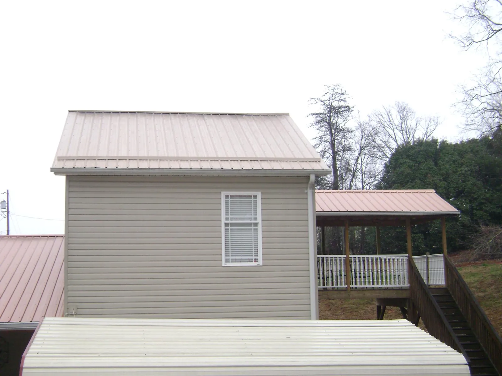 Tan metal roofs on a two story addition and attached porch, from a Roof Replacement job in Newton Hamilton