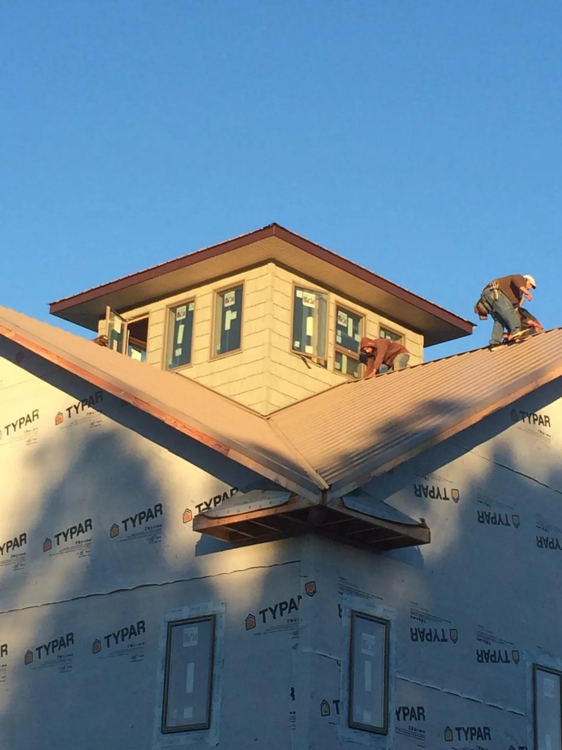 Roofers working around a rooftop cupola on a new metal roof at sunset — Roof Waterproofing in Newton Hamilton by Roofing Brothers